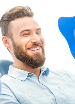 man smiling while holding dental mirror 