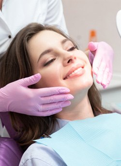 woman smiling while holding dental mirror 