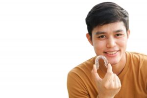 closeup of a man holding Invisalign near his mouth
