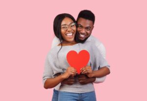 smiling couple hugging and holding a red heart